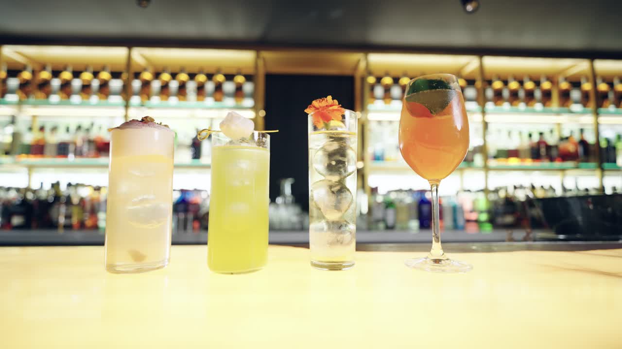 Quattro cocktail colorati allineati su un bancone del bar