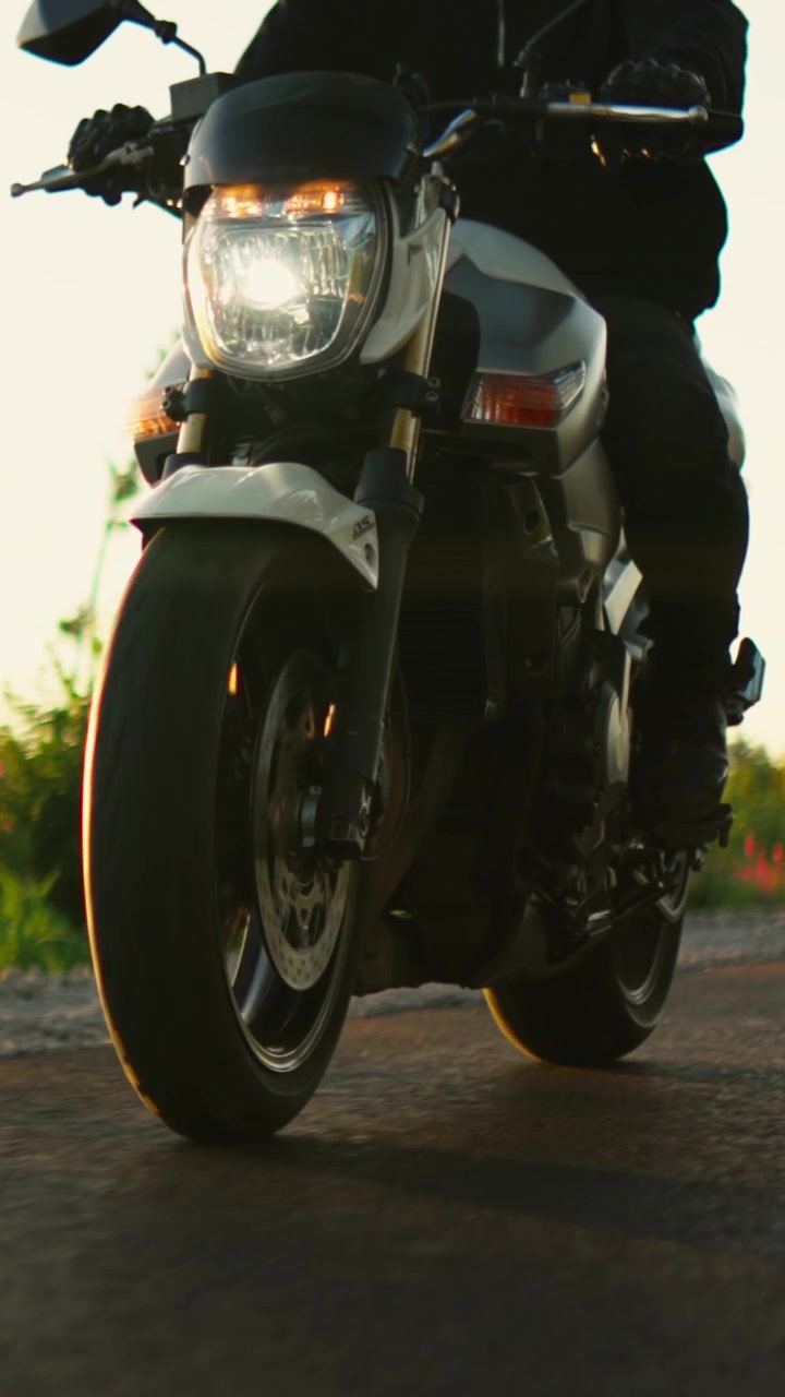 Motociclista Pilotando em uma Estrada Rural ao Pôr do Sol
