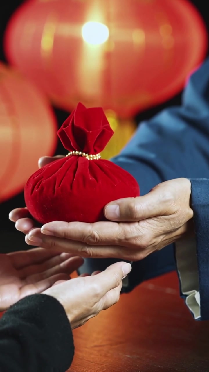 Vertical video: Presenting blue giver offering red pouch over table at festival, receiver palms up