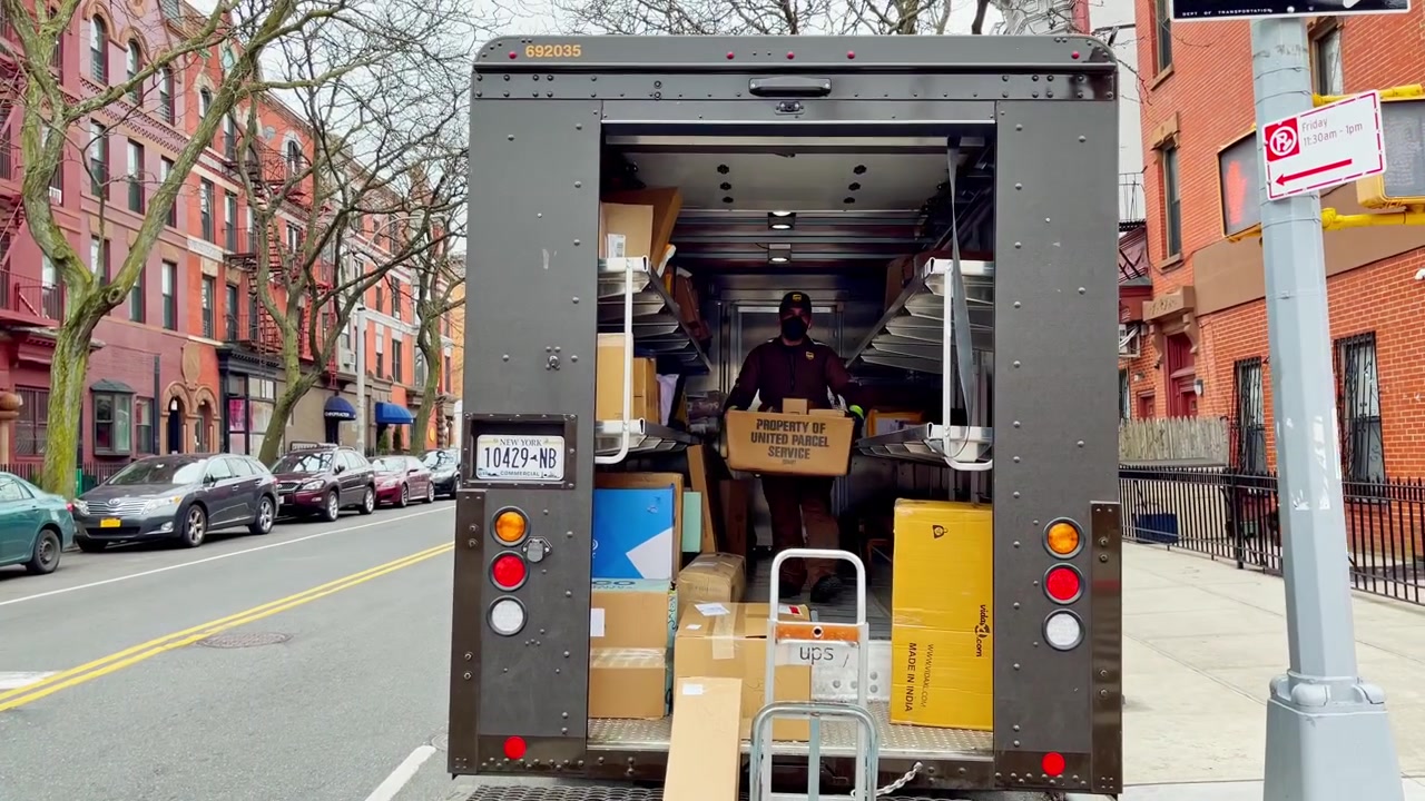New York, VS, 9 maart 2022: Bezorgmedewerker laadt pakketten in open vrachtwagen op stadsstraat