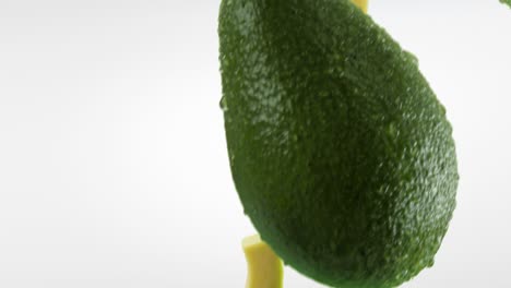 aguacate con rebanadas que caen sobre un fondo blanco