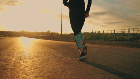 Corredora-Profesional-Está-Entrenando-Al-Aire-Libre-Al-Atardecer-O-Al-Amanecer-Vista-Trasera-De-Las-Piernas-La-Mujer-Está-Trotando