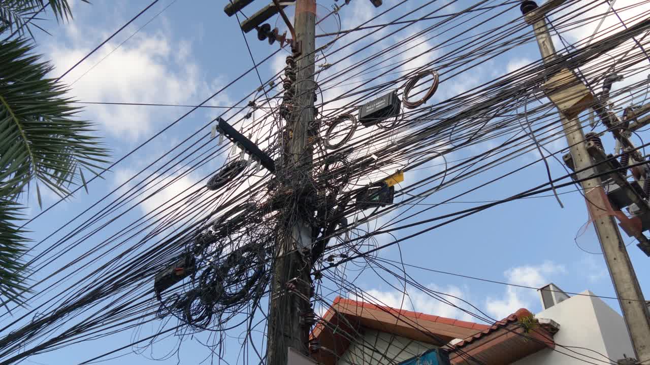 Electricity pole with tangled wires under a blue sky in Ao Nang, Krabi, Thailand