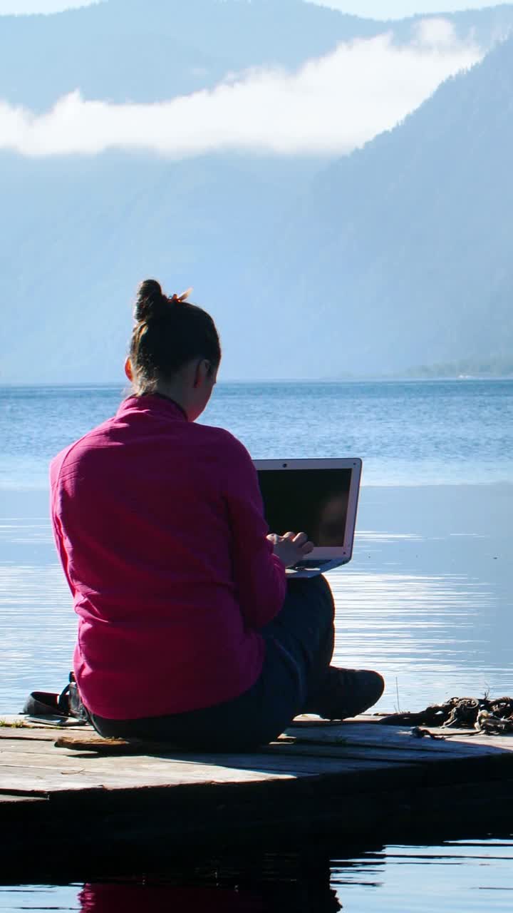 Woman working on a laptop by the lake
