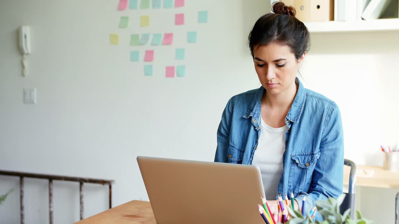 ejecutiva sentada en un escritorio y usando una computadora portátil