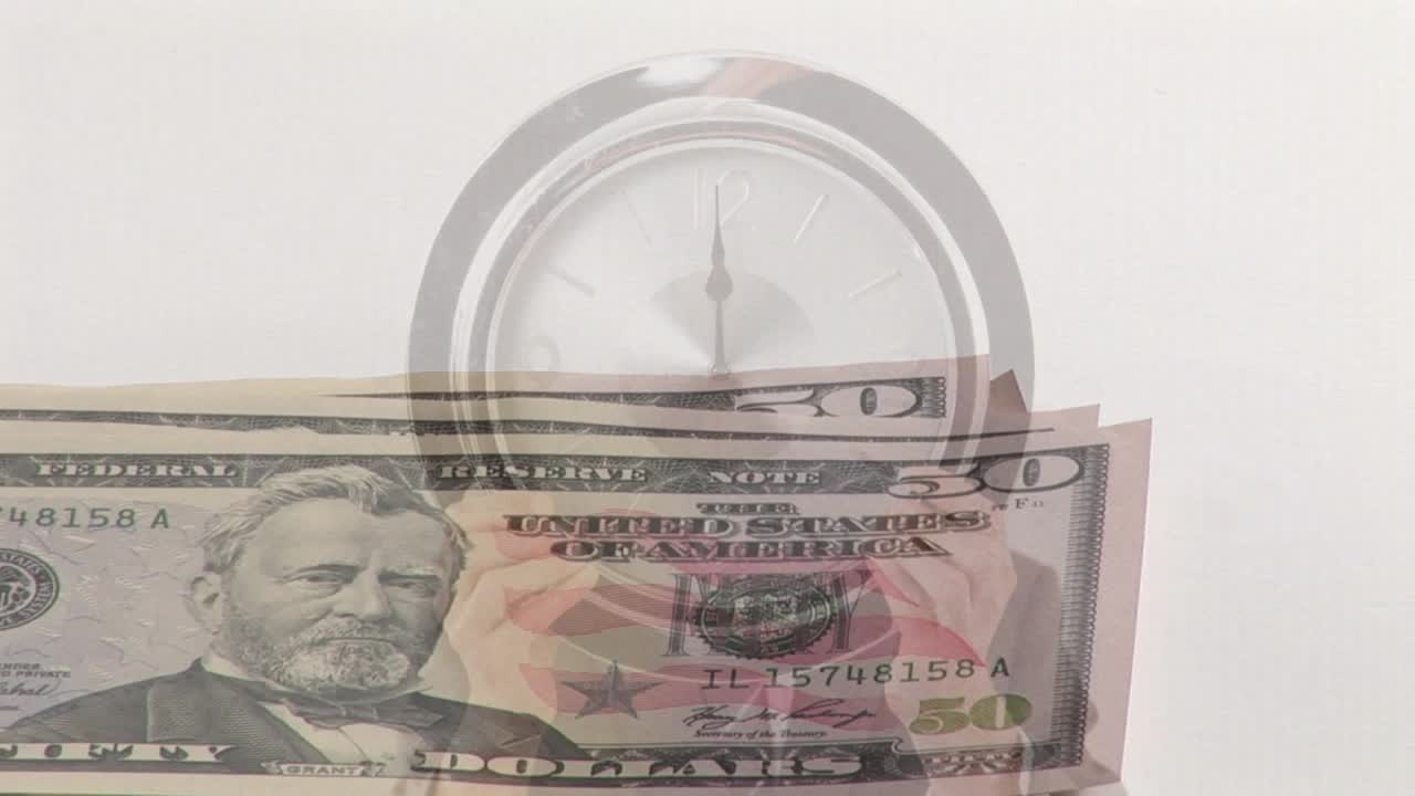Tumpukan uang lima puluh dolar masuk dari kiri bawah, tangan mengipasi dan memindahkan uang kertas, memperlihatkan jam