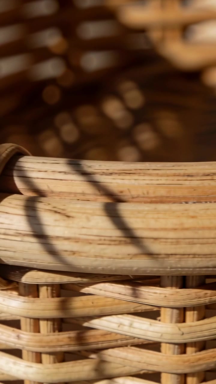 Video verticale: Telecamera che scorre lungo il bordo in rattan e una bobina avvolta su un patio soleggiato, rivelando l'intreccio.