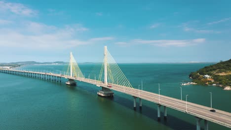 cinematic aerial shot ofanita garibaldi bridge above the turquoise color brazilian ocean, located in laguna, santa catarina, brazil