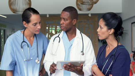 Front-view-of-multi-ethnic-doctors-discussing-over-digital-tablet-in-the-hospital-4k