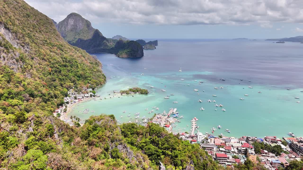 Drone reveals El Nido’s dramatic karst mountains and Bacuit Bay, with clear waters, white sand coast, and boats anchored along the tropical shoreline in Palawan, Philippines
