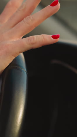 woman in green jacket turns steering wheel moving fingers to music on blurred background. female driver sits in vehicle going home closeup slow motion