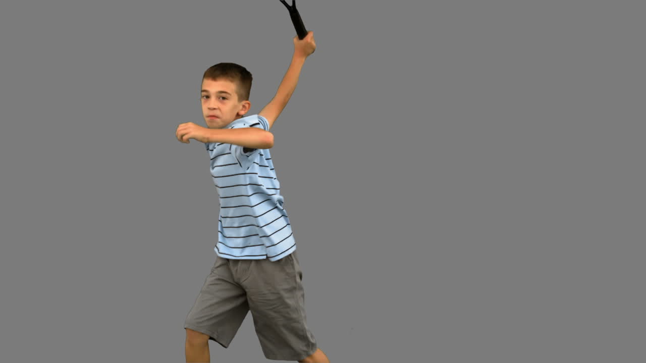 Little boy playing tennis on grey screen