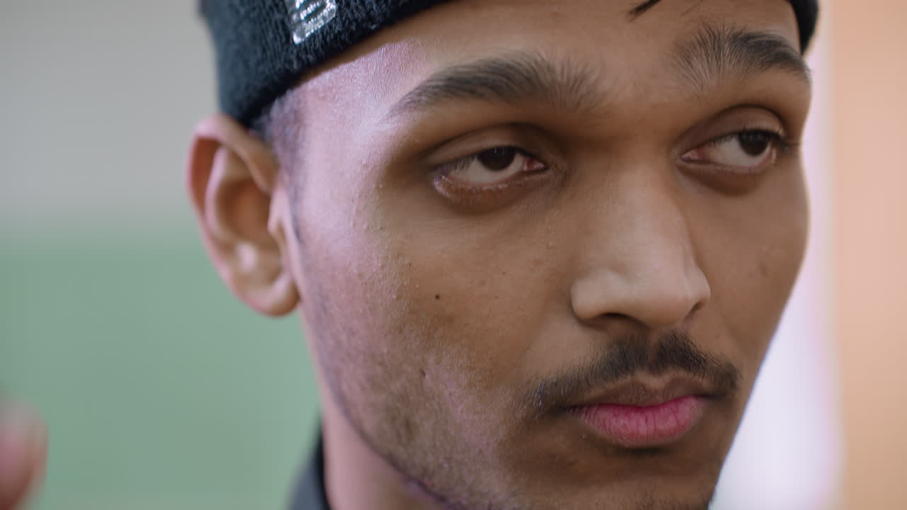 Extreme close up of young man adjusting black headband while looking into distance with focus and determination, highlighting preparation, discipline, and mindset before sports activity