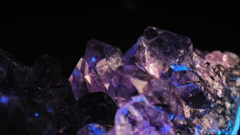 luminous purple amethyst crystal with color-changing lighting against black background