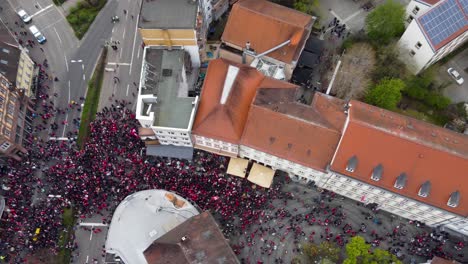 aerial view, drone flying over altstadt main street in kaiserslautern germany on a saturday while fck football club fans celebrating ther victory cheering, drinking beer at street intersection