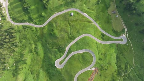 Aerial-view-of-a-single-car-driving-on-the-winding-road-of-Passo-Gardena-in-the-Dolomites-Mountains,-Trentino,-South-Tyrol,-Italy