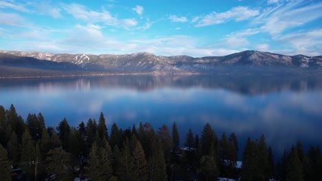 Aerial-View-of-Lake-Tahoe-USA-on-Sunny-Winter-Day,-Calm-Water-Reflections-and-Coastal-Forest