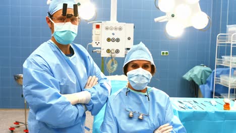retrato de cirujanos masculinos y femeninos con los brazos cruzados en la sala de operaciones