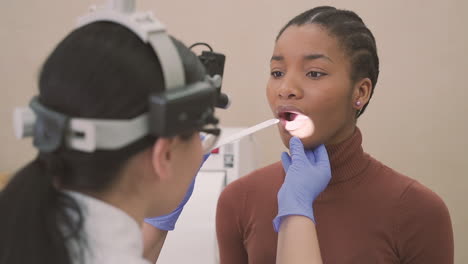 Female-Doctor-Does-A-Medical-Check-Up-In-A-Patient's-Mouth,-A-Young-Girl