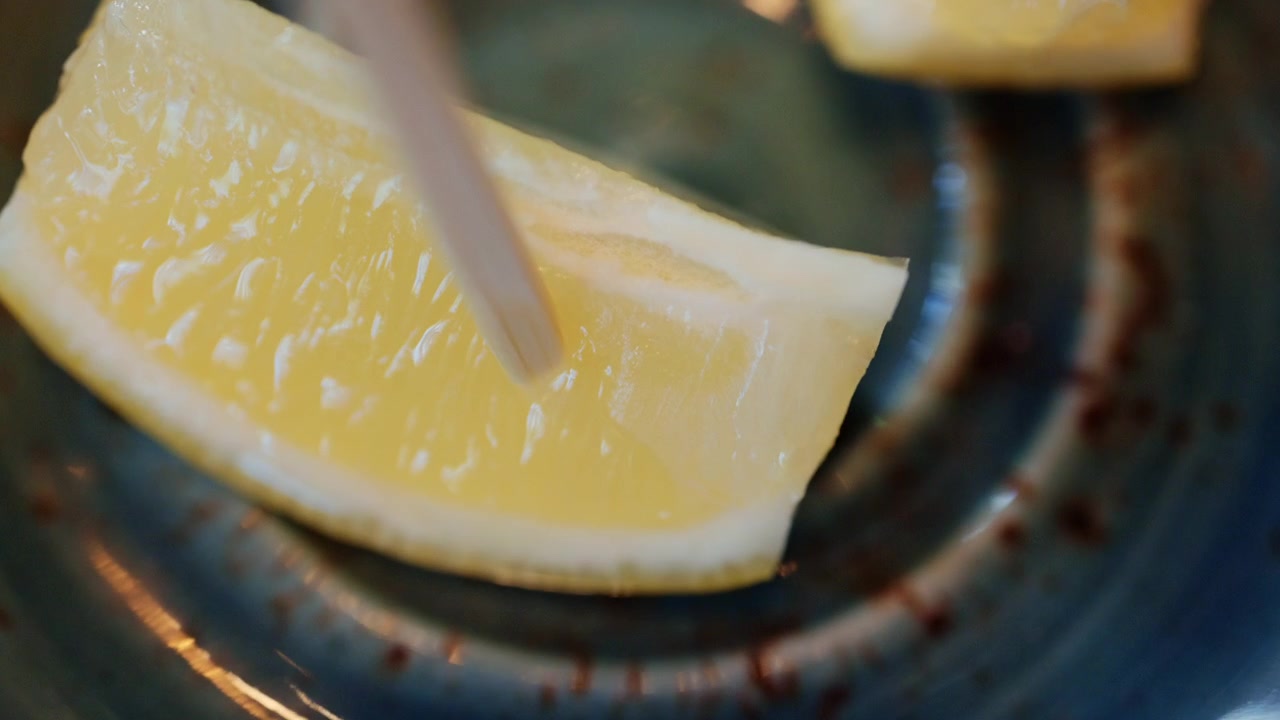 Fette di limone posizionate su un piattino, con un bastoncino di legno inserito nel frutto.