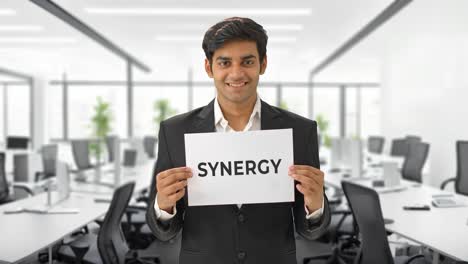 Happy-Indian-manager-holding-SYNERGY-banner