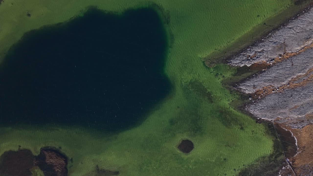 The Burren, County Clare, Ireland - The Landscape Features a Striking Contrast of Dark Waters, Lush Green Terrain, and Rugged Limestone Formations Shaped by Erosion - Close Up