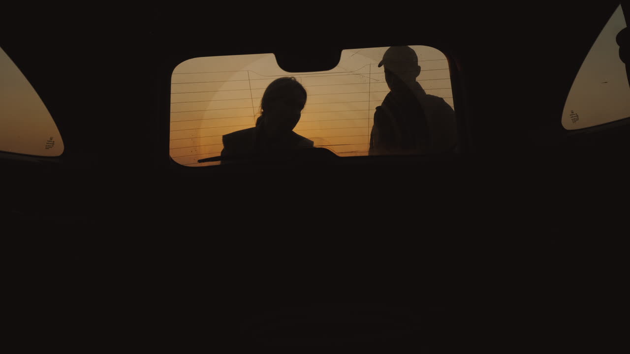 두 사람이 트렁크에서 스페어 타이어를 꺼냅니다.