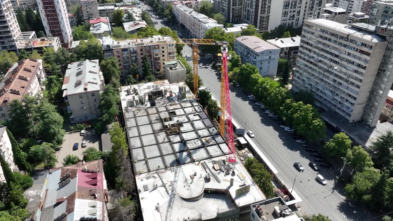aerial video of construction project in a busy urban area. Tower cranes are working amidst residential buildings, showing the development of new city infrastructure and high-rise complexes