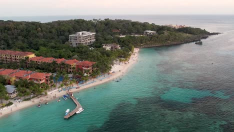 Aerial-view-of-the-coast,-speed-boats,-green-palms-on-the-sandy-beach-at-sunset