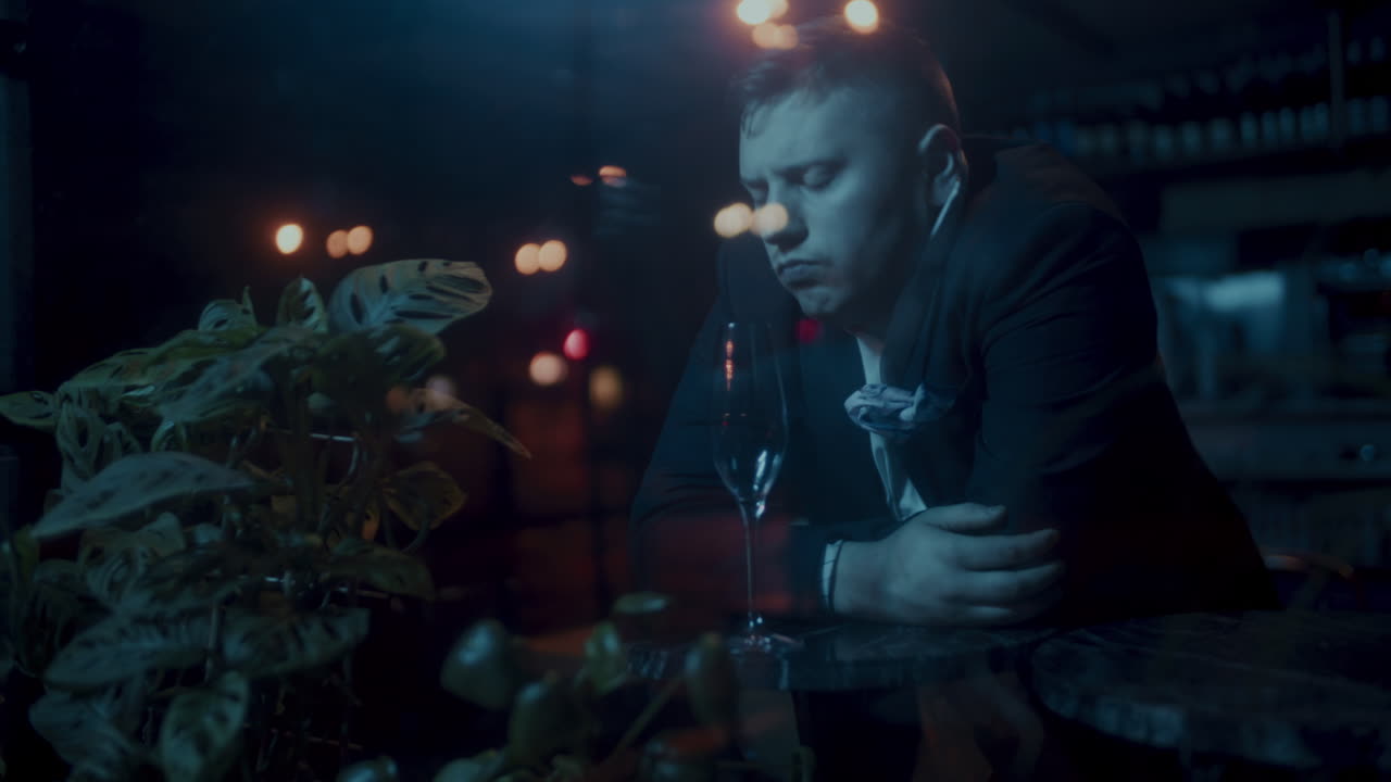 A Man Leaning on a Bar Counter at Night