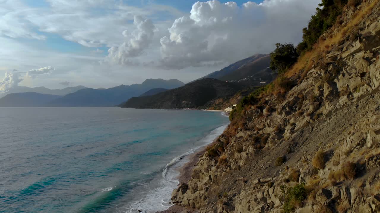 Panorama costiero con colline rocciose sul litorale bagnato dalle onde del mare in una giornata nuvolosa nel Mediterraneo.