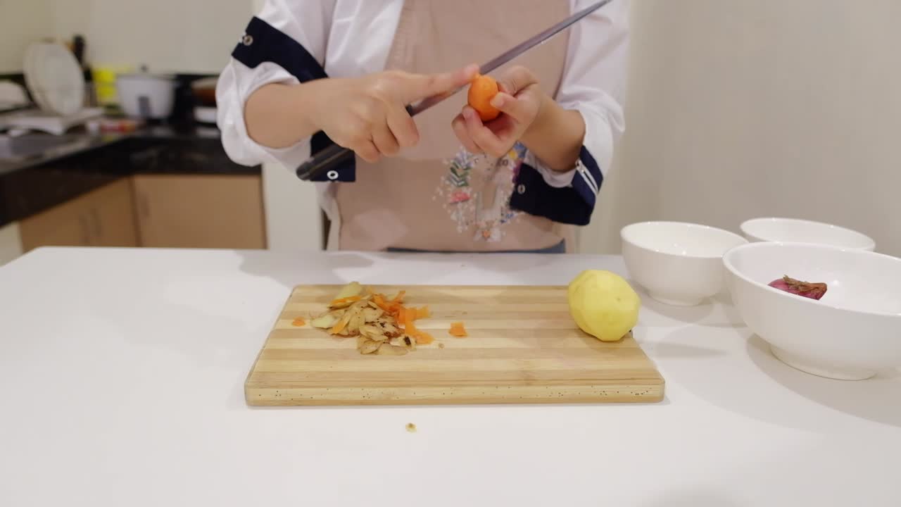 mujer experta cocinero pelando la piel de la zanahoria usando un cuchillo afilado en la cocina