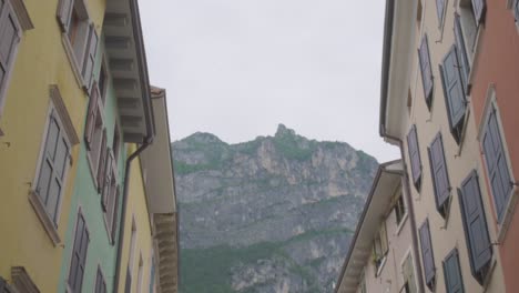 Beautiful-shot-of-the-italian-alps-and-two-colorful-buildings-in-the-center-of-Riva-Del-Garda,-a-small-town-in-the-region-of-Trento-North-Italy