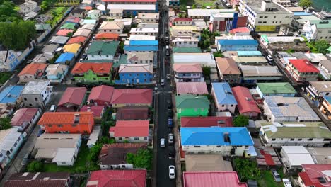 colorful residential neighborhood rooftops and narrow street with parked cars. overhead view of a vibrant, densely-packed community in a tropical region. aerial.