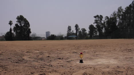 Miniatur-Kickball-Trophäe,-Die-In-Gleitbewegung-Auf-Dem-Feld-Sitzt