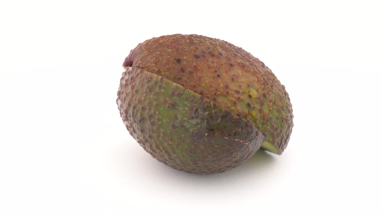 dos rebanadas de aguacate giran lentamente en la mesa giratoria. aisladas en un fondo blanco. macro cerrado.