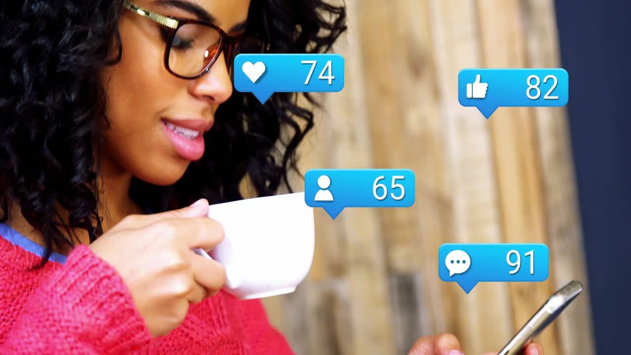 Woman tapping phone at table, checking social media, alerts rising to double digits, sipping mug