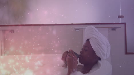 animation of light spots over african american woman taking bath