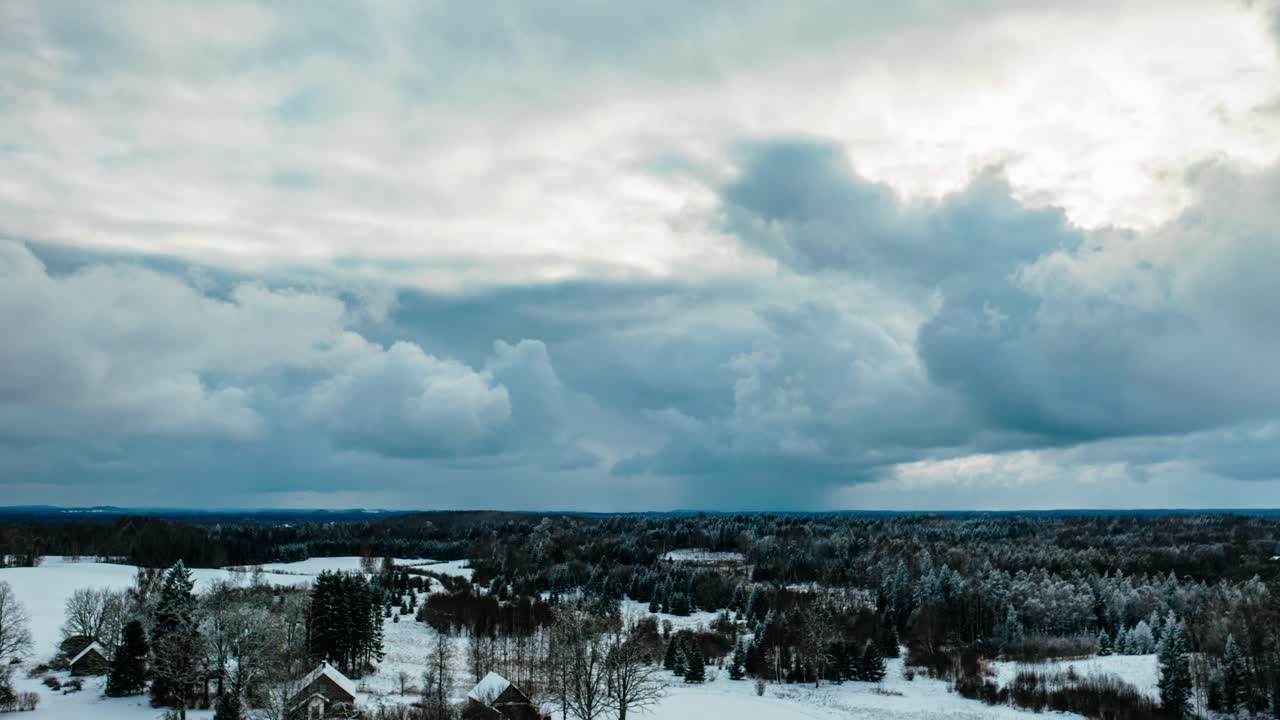 Aerial drone hyperlapse with dark storm clouds over the countryside landscape in winter.