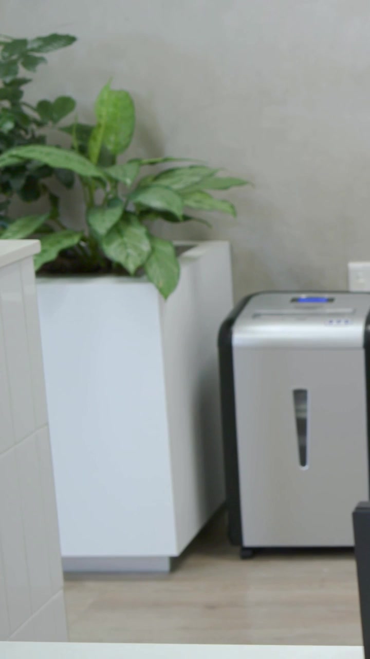 Vertical video: Walking to white tiled counter, man in tan shirt reaching for plant, copy space
