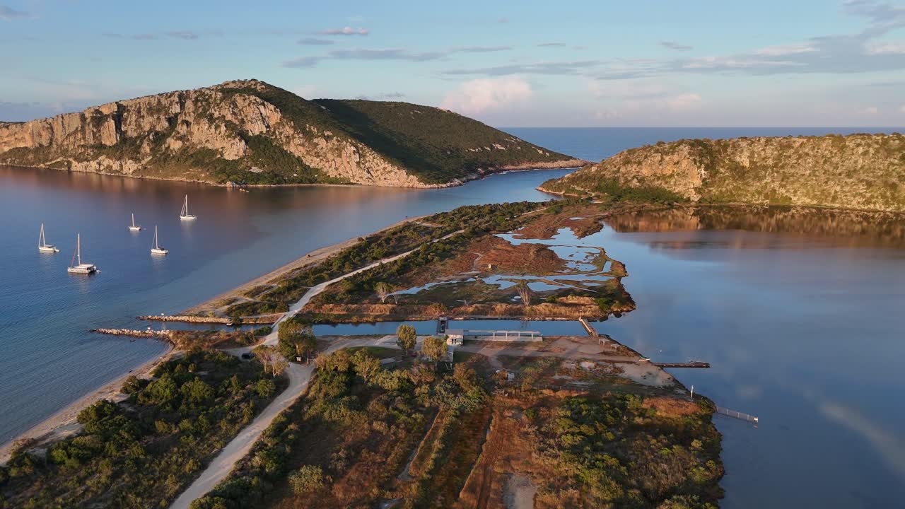 Navarin,Messinia,Gialoval Beach,Aerial view circular pan left from Gialova Lagoon to the Beach.A little channel in between. Lot of sailboats on anchor at the calm bay during sunset.Reflection of cloud