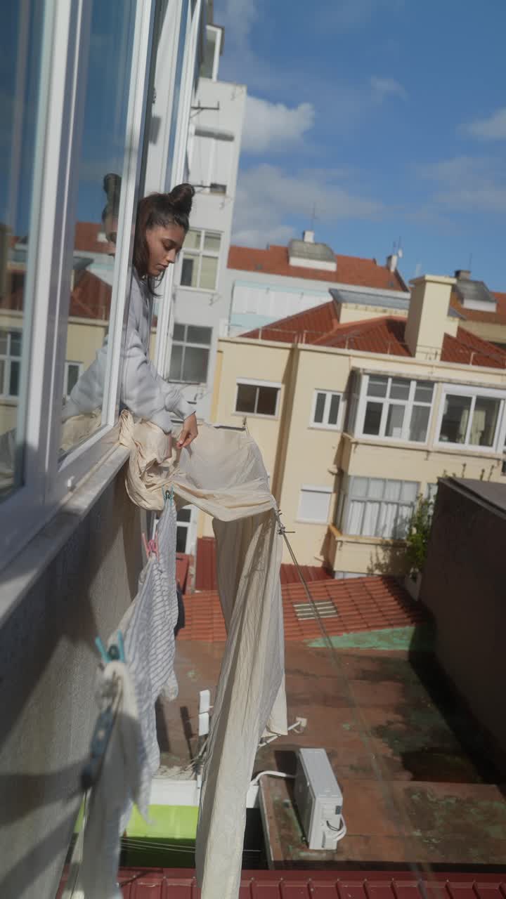 Woman Drying Clothes on Balcony