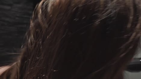 close up rear shot of brunette woman in bathroom drying her wet hairs with dryer in hotel