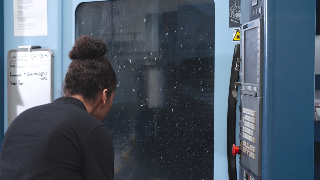 Female Engineer Operating CNC Machinery On Factory Floor
