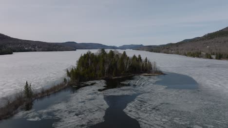 Insel-Am-See-Tremblant-Bedeckt-Mit-Eis,-Das-Nach-Dem-Winter-In-Tremblant,-Kanada,-Zu-Schmelzen-Beginnt