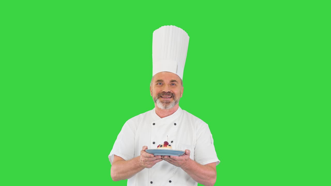 Happy mature chef walking with desert in hands on a Green Screen, Chroma Key
