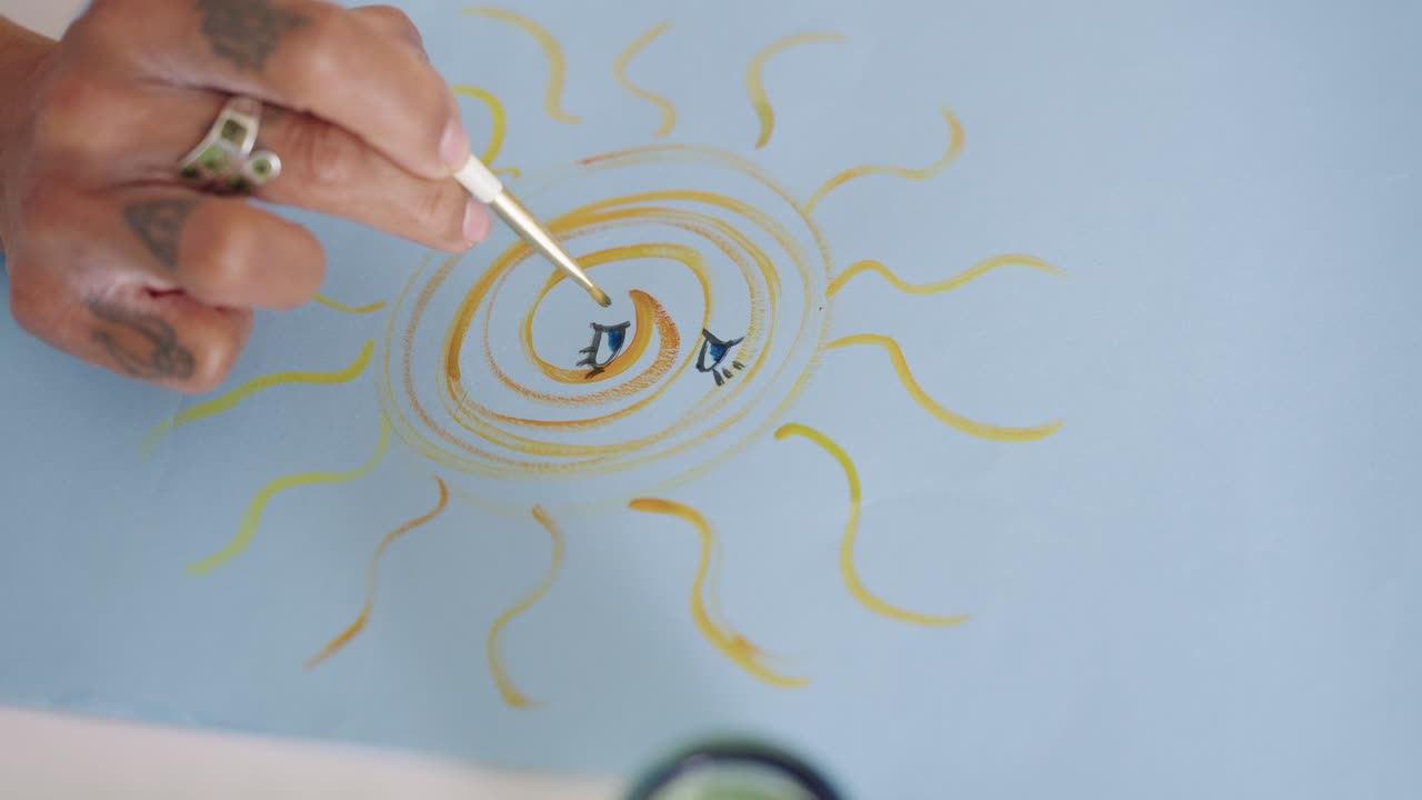Close-Up of Hand Painting a Yellow Sun with Eyes