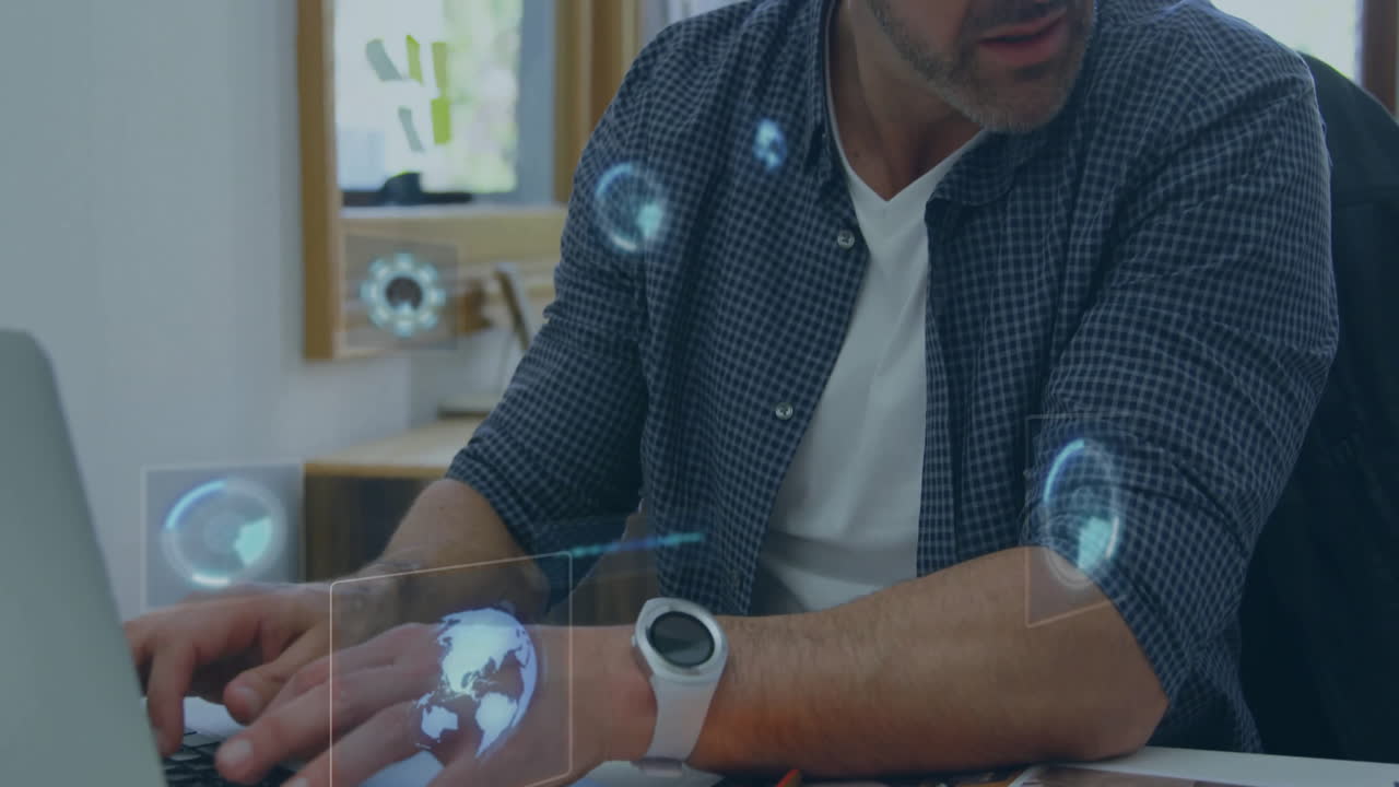 man typing on laptop in home office, displaying holographic globe and loading icons for technology