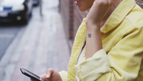 mujer de raza mixta usando un teléfono inteligente en la calle
