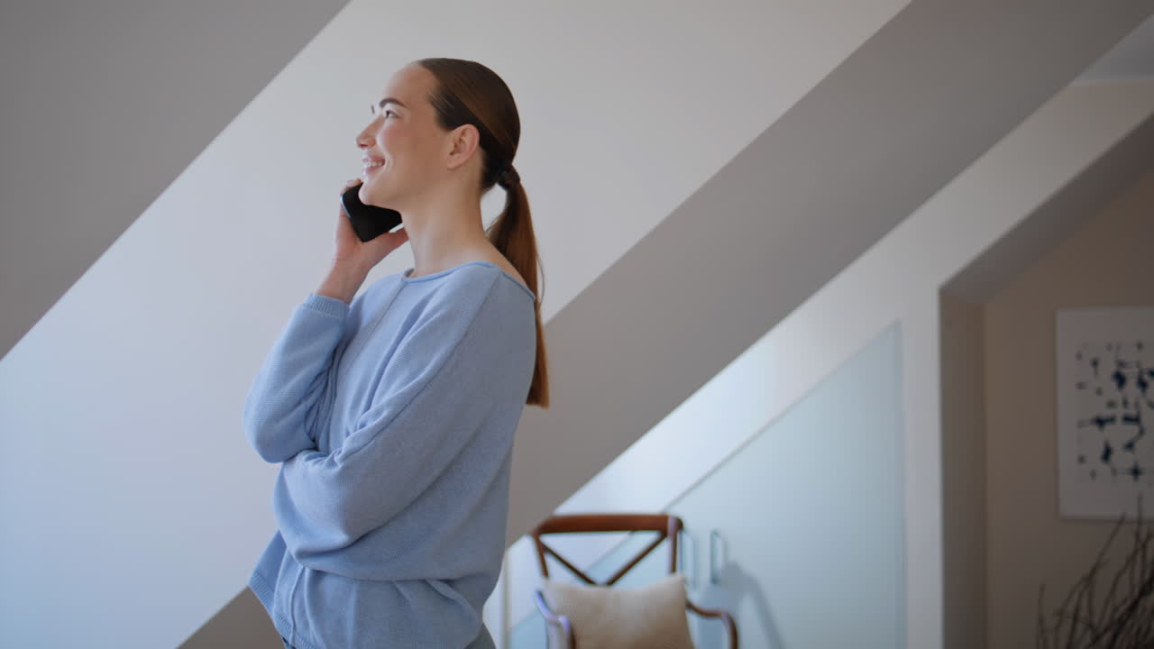Thoughtful girl talking smartphone in living room positive expression closeup